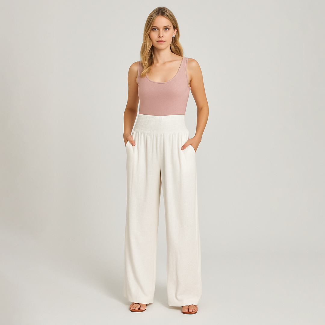 Wide-leg linen-blend pants with pleated front and smocked high waist, styled for relaxed summer beachwear