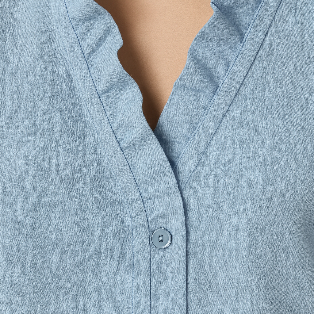 Blouse with V-neckline and ruffle trim along neckline and cuffs.