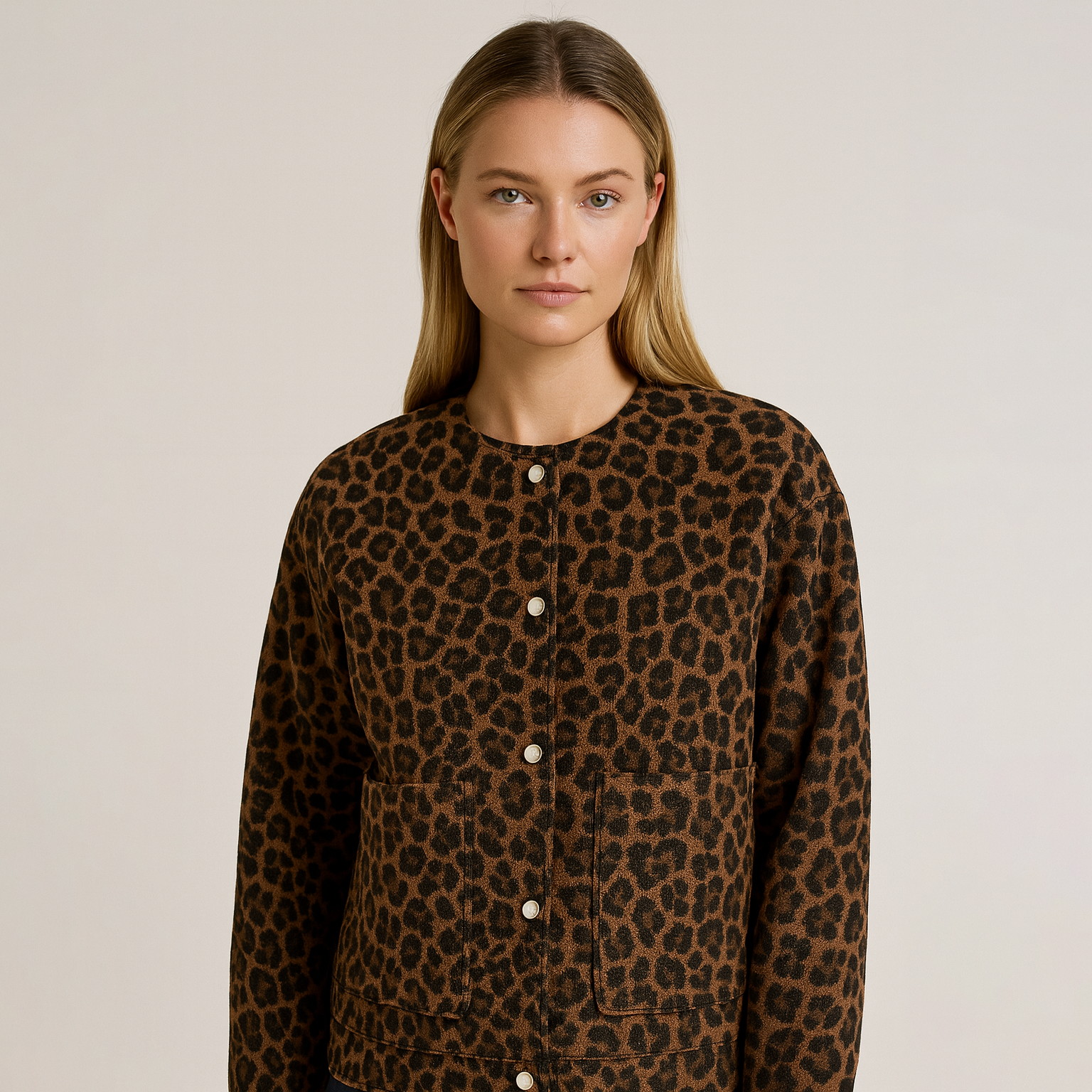 Cozy leopard print jacket with button front, hip length, and relaxed fit, styled with dark jeans and a black top.