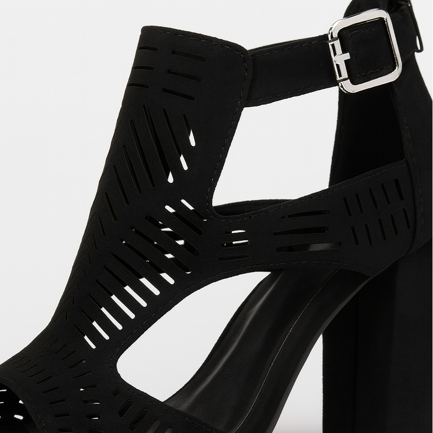 Black faux suede block heel sandals with cut-out design, open toe, and ankle strap with buckle fastening.
