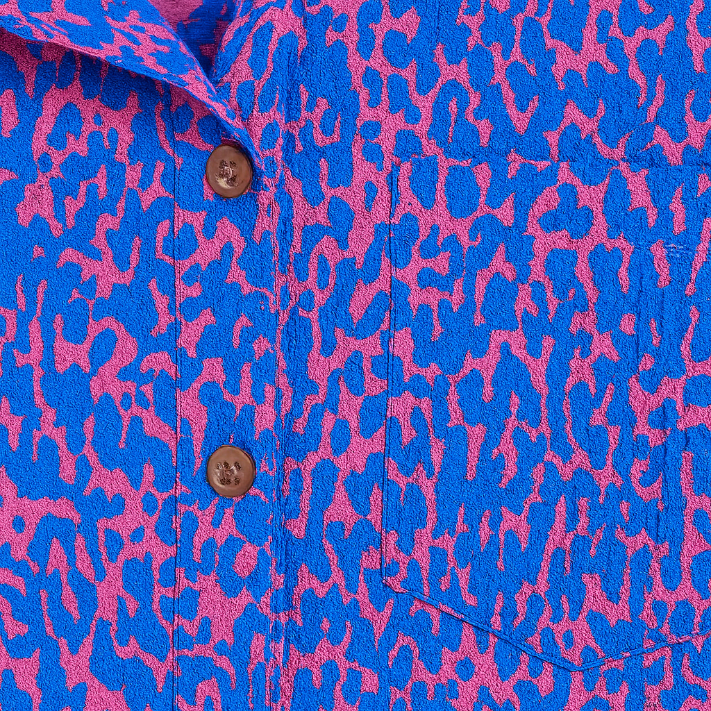 Button-up shirt with a bold blue and pink abstract animal print, featuring a pointed collar and long sleeves.
