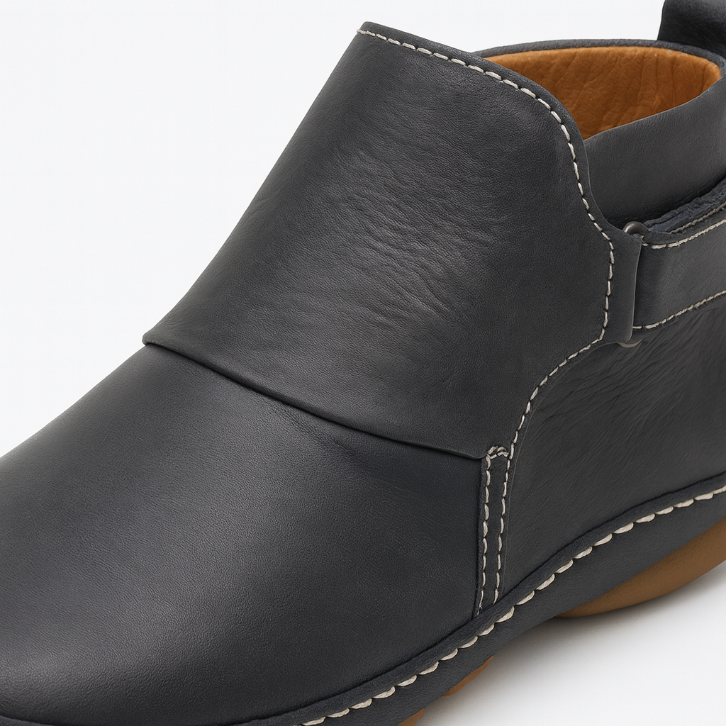 Ankle boot with slip-on design, contrast stitching, and flat sole.