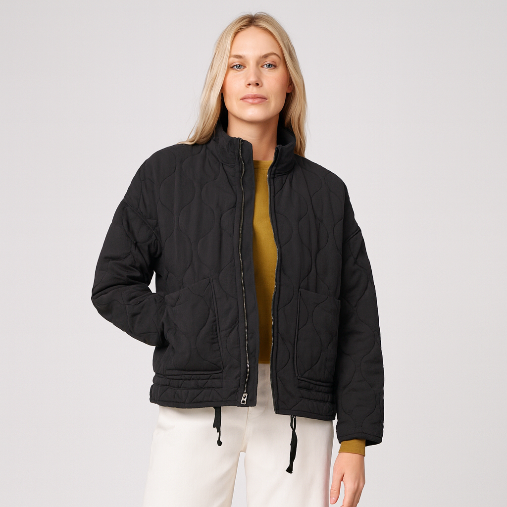 A quilted jacket featuring a high collar, full front zipper, and relaxed fit. Designed with wave-pattern stitching, two large front patch pockets, and adjustable drawstrings at the hem for a customizable fit. A minimalist yet functional outerwear piece perfect for layering in cooler weather.