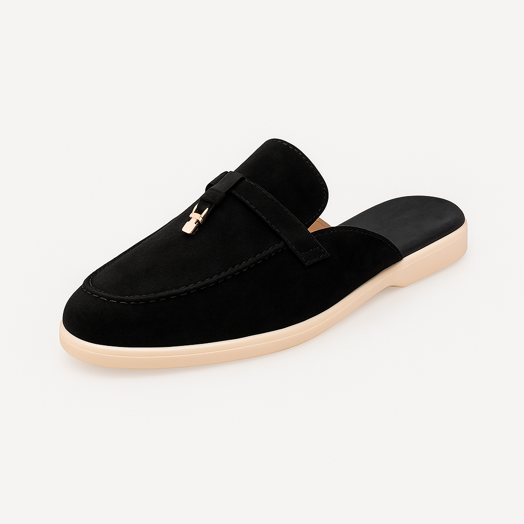 Suede mule loafer with a rounded toe, decorative strap, metal accent, and flat sole.