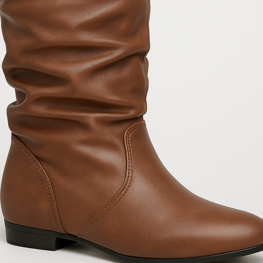 Faux leather slouch knee-high boots with pointed toe and flat sole, styled for casual everyday wear.