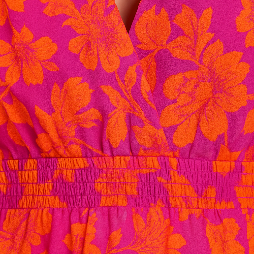 Bright pink and orange floral midi dress with puff sleeves, deep V-neckline, and flowy skirt, styled with neutral heels and a clutch.