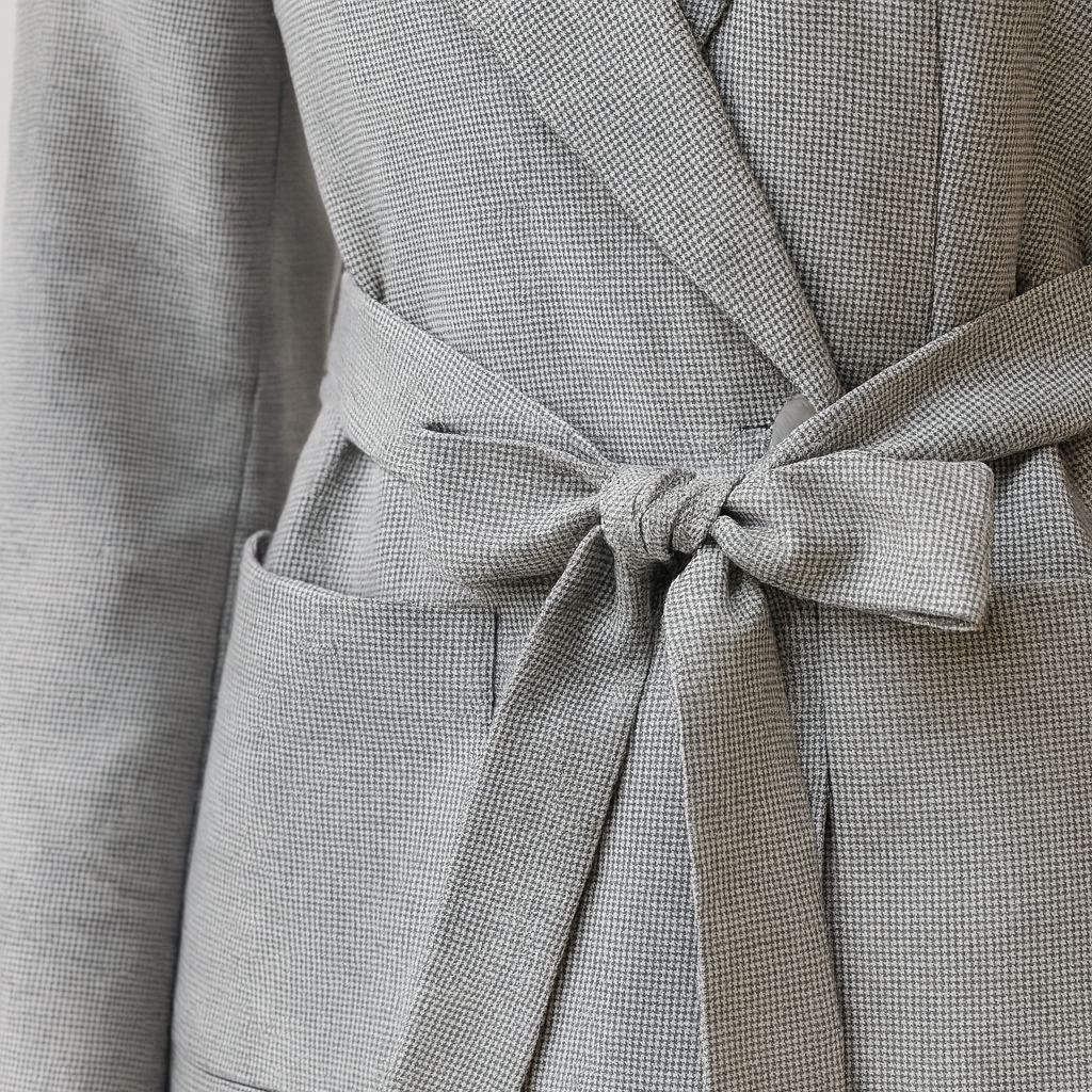 A blazer with long sleeves, a wide notched lapel, and a waist tie belt.