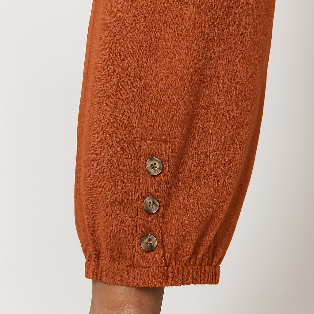 Relaxed jogger pants with elastic waistband, patch pockets, and buttoned hem details, styled for casual everyday wear