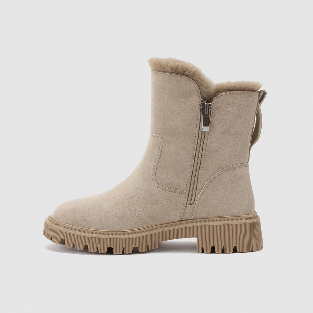 A mid-calf winter boot with a soft suede exterior, side zipper closure, pull tab at the heel, faux-fur lining, and a chunky ridged sole.
