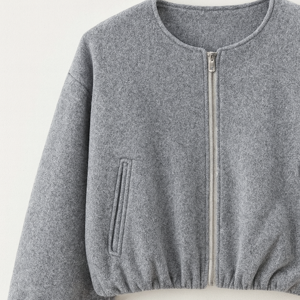 A zip-up jacket featuring a minimalist round neckline, dropped shoulders, and oversized balloon sleeves. The design includes front slit pockets and a gathered hem, creating a relaxed, casual silhouette perfect for layering in cool weather.