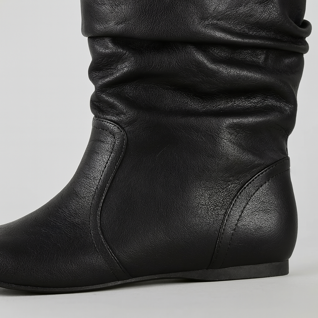 A sleek mid-calf boot with a slouchy leather design and rounded toe. The flat sole provides comfort and ease for everyday wear, while the soft, gathered texture adds a touch of casual sophistication to the minimalist silhouette.